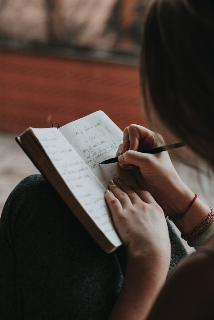 An open journal with handwritten notes, a pen, and a cup of tea on a cozy kitchen table.